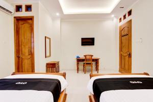 two beds in a room with a table at Collection O 94154 Puri Gusti Ayu in Yogyakarta
