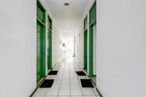 a hallway with green doors and a white tile floor at Hotel O Gurita in Solo