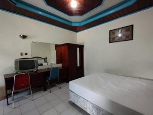 a bedroom with a bed and a desk and a tv at Hotel O Wisma Bunda Syariah Near Man Pinrang in Salo