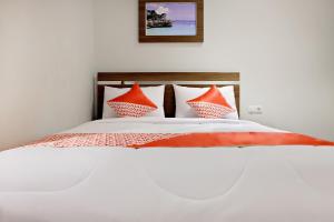 a bed with orange and white pillows on it at Super OYO 2756 Anata in Makassar