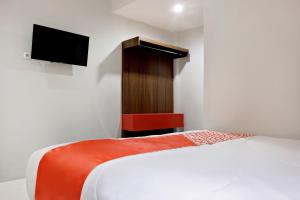 a bedroom with a bed and a flat screen tv at Super OYO 2756 Anata in Makassar