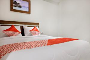 a large white bed with red pillows on it at Super OYO 2756 Anata in Makassar
