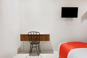 a room with a desk and a bed and a television at Super OYO 2756 Anata in Makassar +16 photos