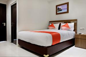 a bedroom with a large bed with orange and white pillows at Super OYO 2756 Anata in Makassar