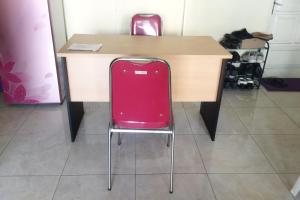 a red suitcase sitting on a chair next to a table at Hotel O Rumah Singgah Cemara Syariah in Pekanbaru