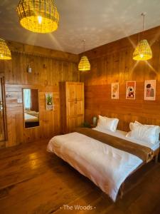 a bedroom with a large bed with wooden walls at The Woods - Tirthan Valley in Gushaini