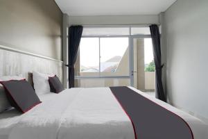 a bedroom with a large bed with a large window at Capital O 1898 Louise Place in Cianjur