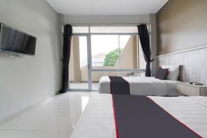 a hotel room with two beds and a television at Capital O 1898 Louise Place in Cianjur +25 photos