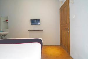 a room with a bed and a wooden door at Capital O 1898 Louise Place in Cianjur