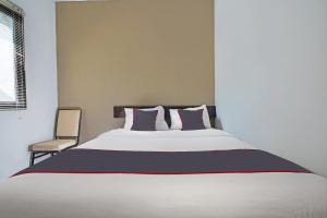 a bedroom with a large bed and a chair at Capital O 1898 Louise Place in Cianjur