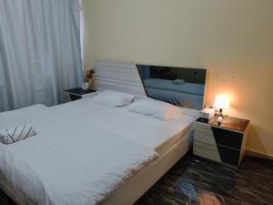 a bedroom with a large white bed with a night stand and a lamp at Summer home stay 04 in Abu Dhabi
