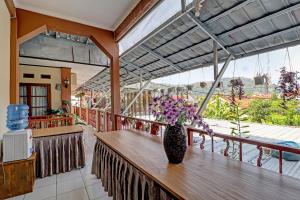 eine Vase mit Blumen auf einem Tisch auf einem Balkon in der Unterkunft OYO Life 91480 Putridapisa Syariah in Sumedang