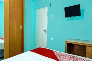 a bedroom with a bed and a tv on a blue wall at Hotel O Home Stay Elis Cateliya Syariah in Karawang