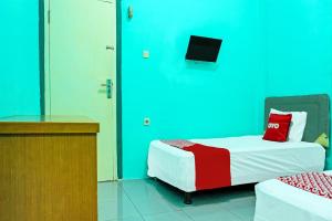 a room with a bed with a tv on the wall at Hotel O Home Stay Elis Cateliya Syariah in Karawang +27 photos