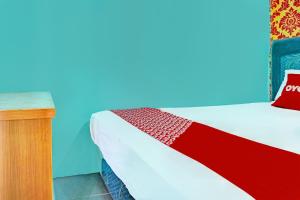 a bedroom with a bed with a red and blue wall at Hotel O Home Stay Elis Cateliya Syariah in Karawang