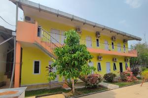a yellow building with a tree in front of it at Hotel O Garuda Bandara Guesthouse in Palembang