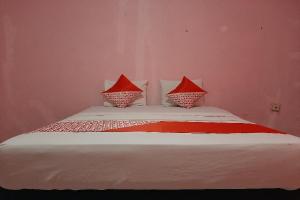 a bedroom with a bed with red and white pillows at OYO 90555 Vina Pavilion in Bengkulu