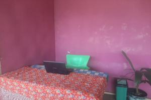 a bedroom with a laptop on a bed with a pink wall at OYO 90555 Vina Pavilion in Bengkulu
