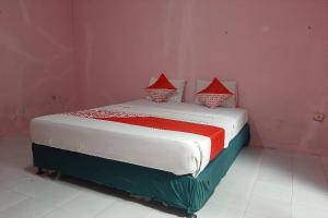 a bedroom with a bed with red pillows on it at OYO 90555 Vina Pavilion in Bengkulu