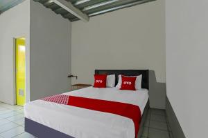 une chambre avec un grand lit avec des oreillers rouges dans l'établissement OYO 90809 Homestay Black Pink Merah Jambu Syariah, à Garut