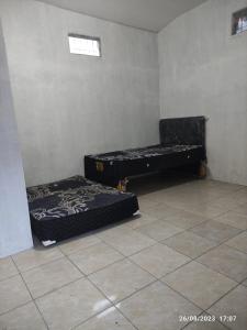 two beds in a room with a tile floor at Hotel O Lina Homestay Syariah in Sedati