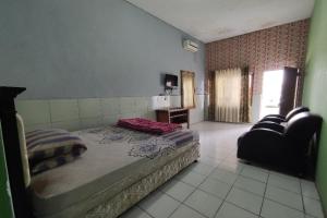 a bedroom with a bed and a couch and a chair at SPOT ON 91105 Hotel Salsabila in Magelang
