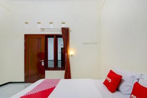 a bedroom with a bed with red pillows on it at Capital O 90151 Guest House 180 in Batu