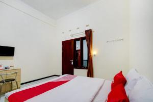 a bedroom with a bed with red pillows and a desk at Capital O 90151 Guest House 180 in Batu