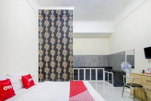 a room with a bed and a kitchen in it at Capital O 90151 Guest House 180 in Batu