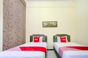 two beds in a room with red pillows at Capital O 90151 Guest House 180 in Batu +23 photos
