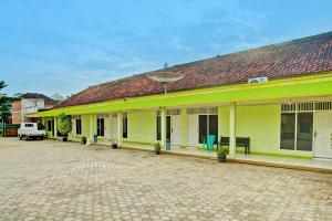 a large yellow building with a red roof at Hotel O Sejahtera Syariah in Umbulan Tulungmeris