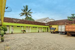 a building with a palm tree in the background at Hotel O Sejahtera Syariah in Umbulan Tulungmeris