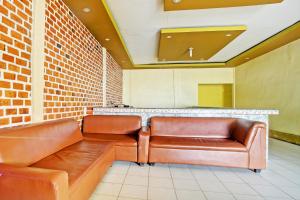 two brown leather seats in a room with a counter at Hotel O Sejahtera Syariah in Umbulan Tulungmeris +44 photos