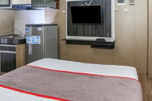 a room with a bed with a tv and a refrigerator at Capital O 93372 Aurora Residence in Tangerang