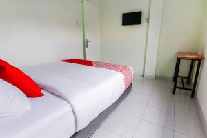 Un dormitorio con una cama blanca con una almohada roja. en Hotel O Nami House, en Medan