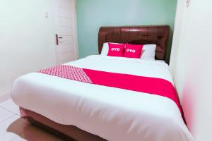 Una cama con dos almohadas rojas encima. en Hotel O Nami House, en Medan
