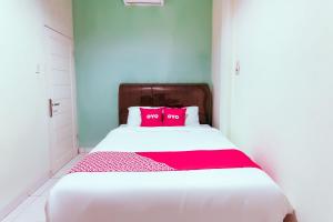 Una cama blanca con dos almohadas rosas. en Hotel O Nami House, en Medan