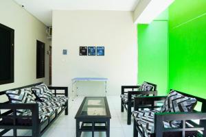 a room with four chairs and a table and a green wall at OYO Life 3078 Kost Putri Made in Surabaya