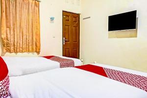 two beds in a room with a tv on the wall at Hotel O Lily House in Tangerang