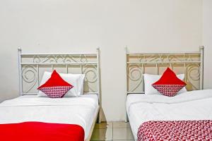 two beds with red pillows sitting next to each other at Hotel O Lily House in Tangerang