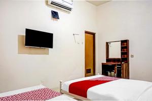 a bedroom with a bed and a tv on the wall at Hotel O Lily House in Tangerang