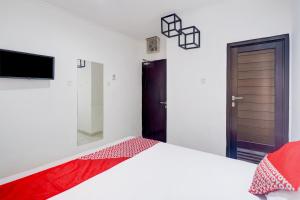 a white bedroom with a bed and a tv at Townhouse Oak Ancol in Jakarta