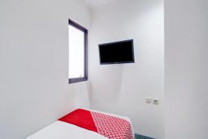 a white room with a bed and a tv on the wall at Townhouse Oak Ancol in Jakarta