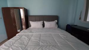 Hotel O Pinus Jaya SyariahNearTaman Amaryllis Pekanbaru في Palas 2: سرير مع ملاءات ووسائد بيضاء في غرفة النوم