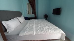 Hotel O Pinus Jaya SyariahNearTaman Amaryllis Pekanbaru في Palas 2: غرفة نوم بها سرير بملاءات بيضاء وتلفزيون
