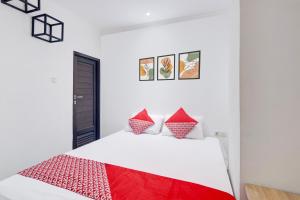 a bedroom with a white bed with red pillows at Townhouse Oak Ancol in Jakarta