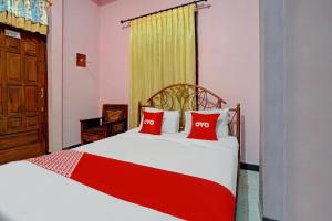 a bedroom with a bed with two red pillows at Hotel O Harwin Homestay in Batu +17 photos