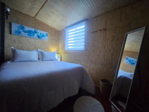 a bedroom with a white bed and a window at Casa Terra, Tu Refugio en la Naturaleza del Sur de Chile in Puerto Montt