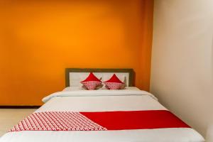 a bed with two red and white pillows on it at OYO 889 Edotel Amanah Hotel Syariah By Smk Muhammadiyah 1 in Pekanbaru +16 photos