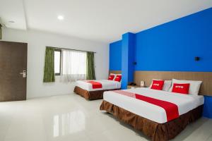 two beds in a room with blue and red at Collection O near Paris Van Java formerly Cassa Dua Hotel in Bandung +50 photos